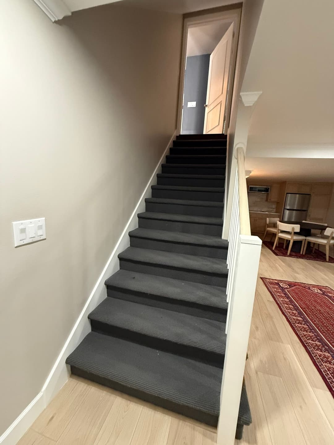 Staircase leading to a light hallway with an open door, modern home interior.