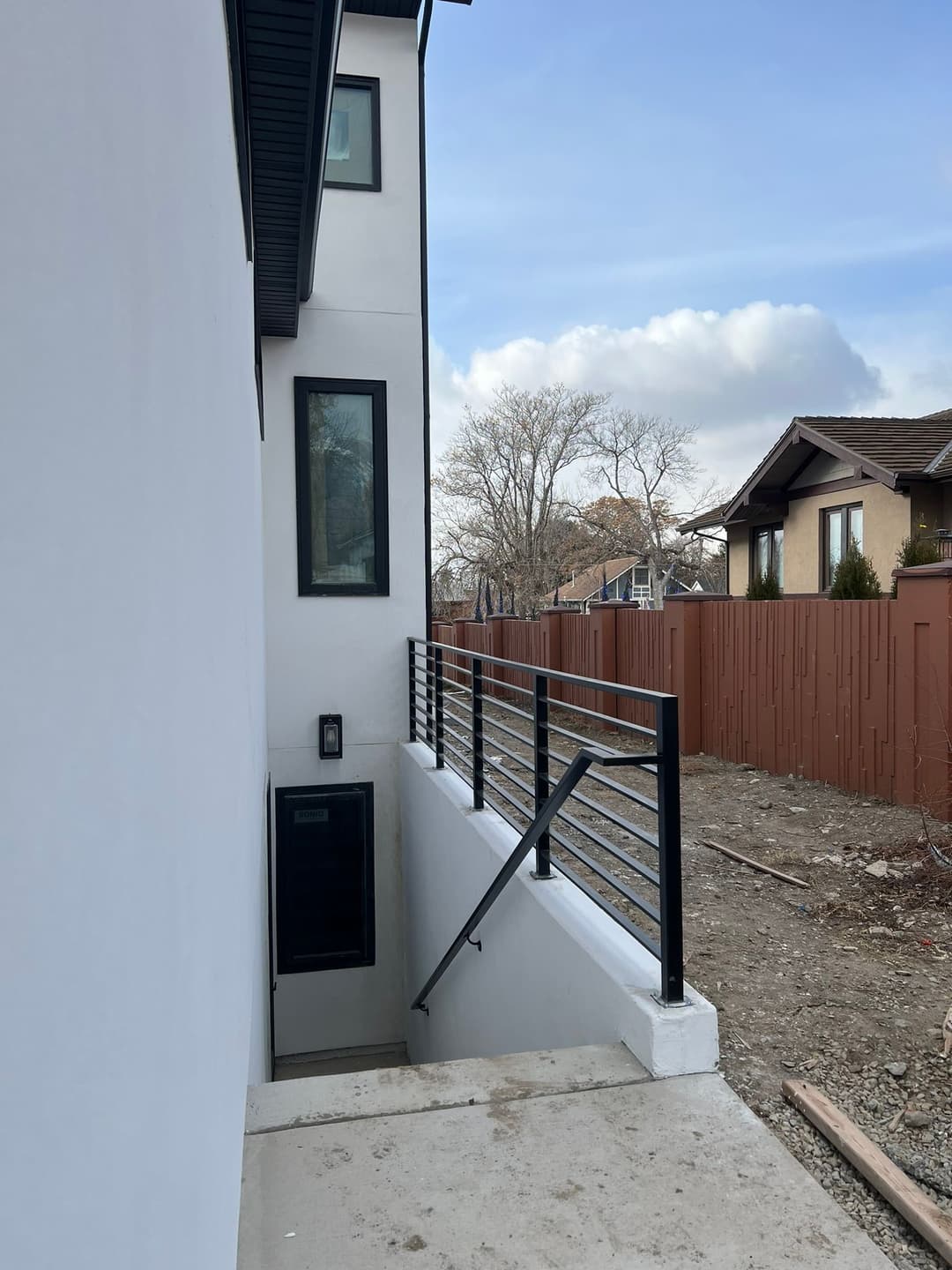 Modern home exterior featuring a side entrance staircase and sleek black railing.