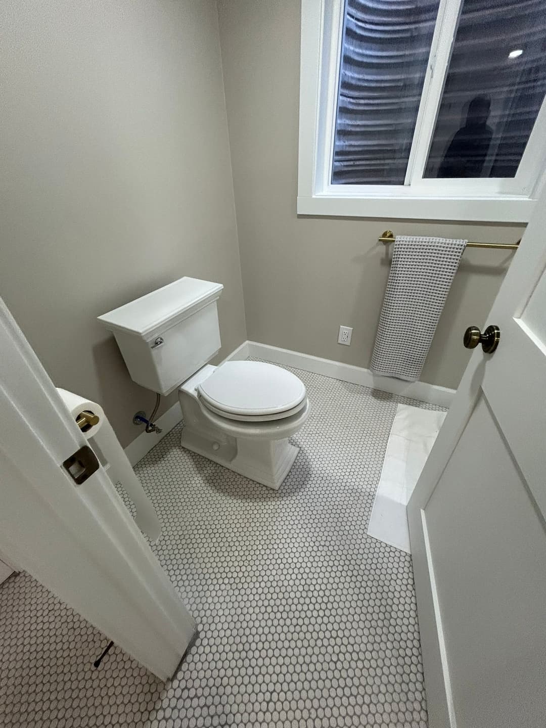 Modern bathroom featuring a white toilet, hexagonal tile flooring, and natural light.