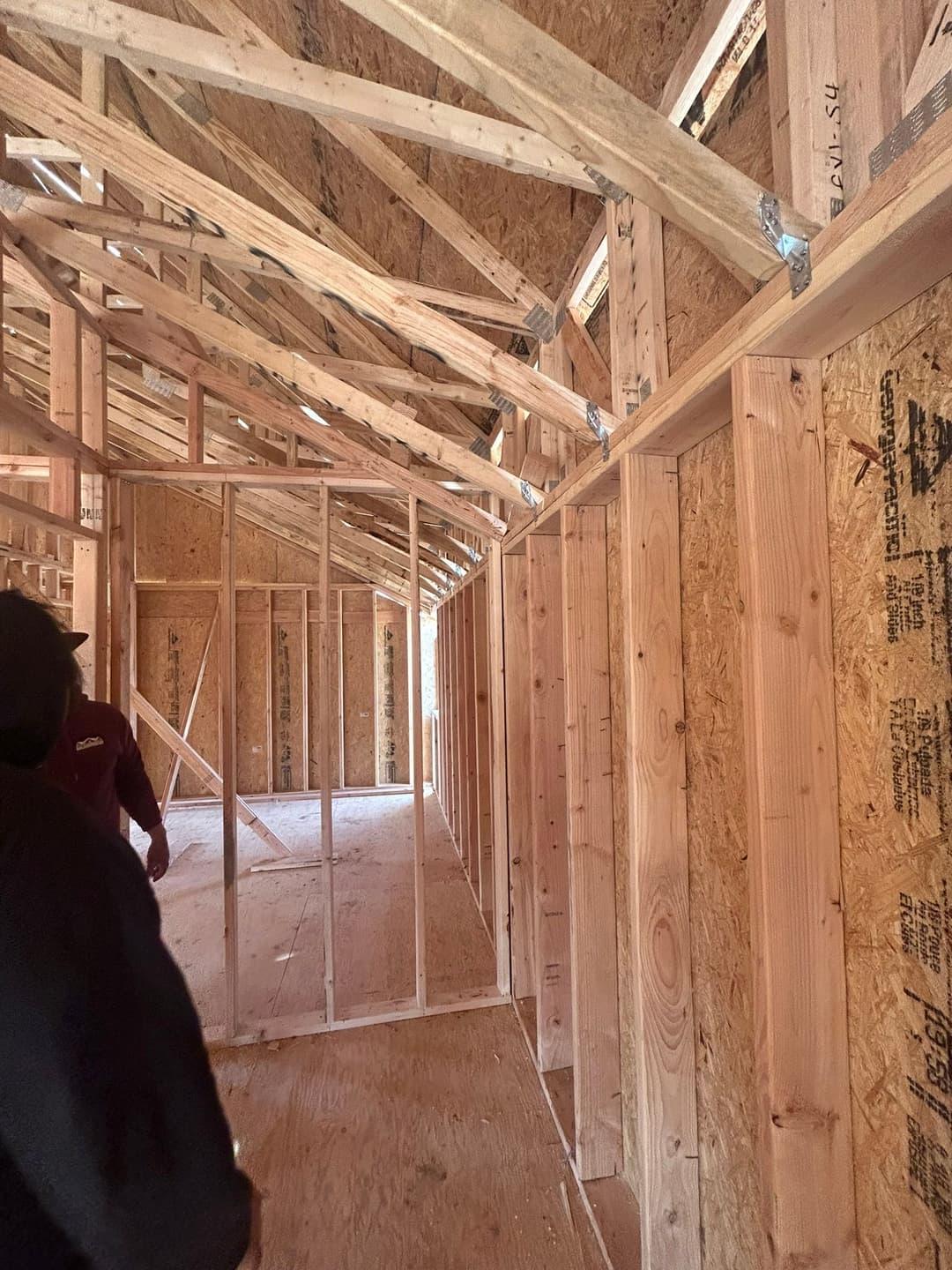 Interior view of a framed house under construction, showing wooden beams and walls.