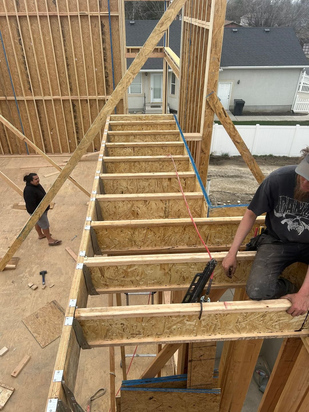 Construction crew building a wooden staircase in a home under construction.