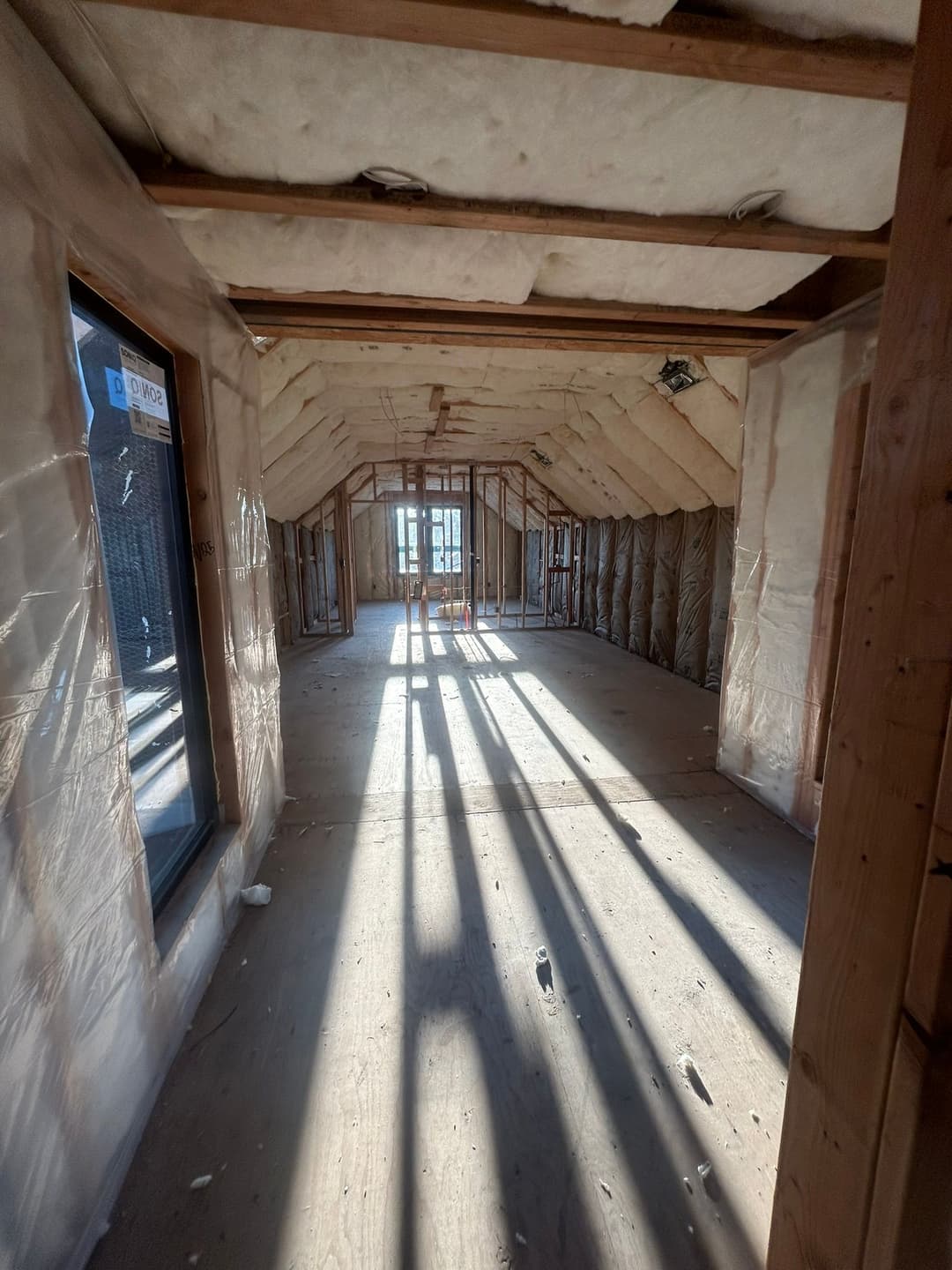 Interior view of an unfinished room with sunlight casting shadows on the floor.