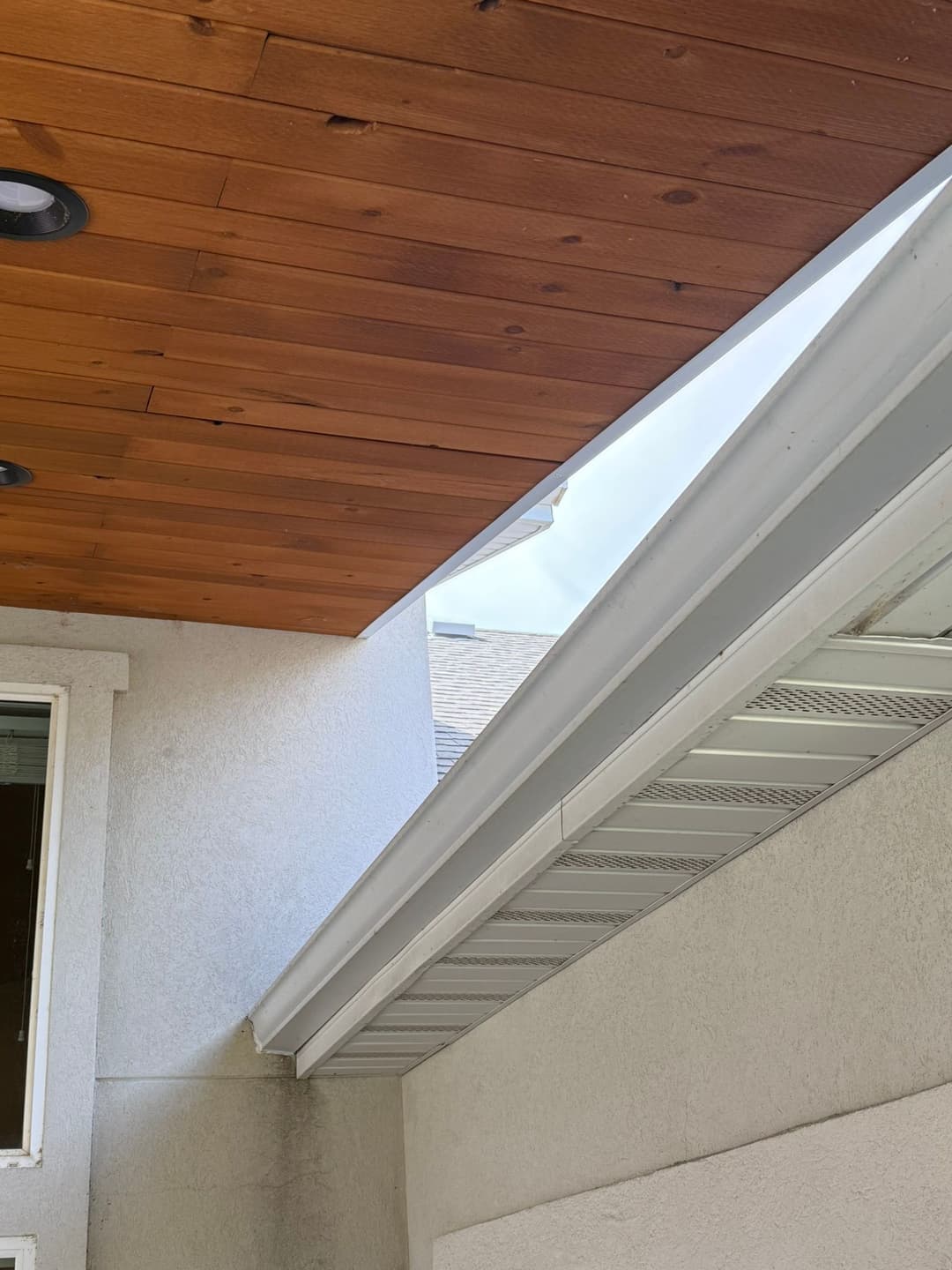 View of a modern home exterior showcasing wooden ceiling and metal gutter system.
